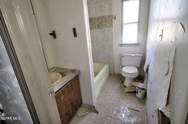 bathroom with a washtub, vanity, and toilet