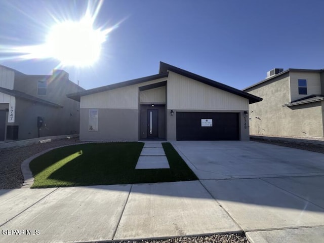 view of front of home featuring central AC, a front lawn, and a garage