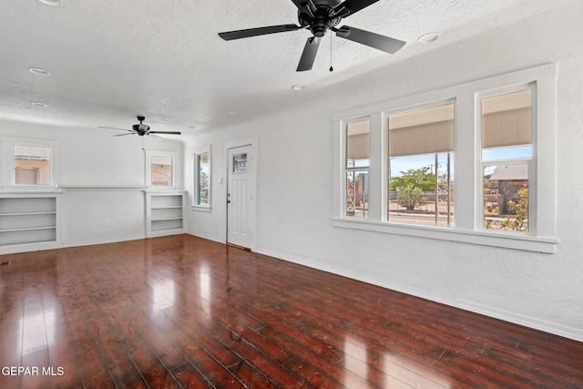 unfurnished living room with built in shelves, ceiling fan, wood-type flooring, and a textured ceiling