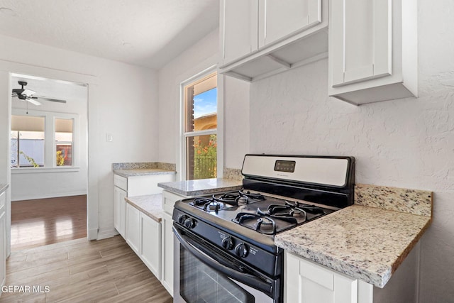 kitchen with white cabinetry, light hardwood / wood-style flooring, black range with gas cooktop, and light stone countertops