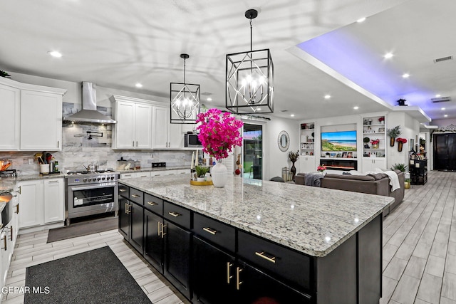 kitchen with wall chimney range hood, a kitchen island, light hardwood / wood-style floors, white cabinetry, and stainless steel appliances