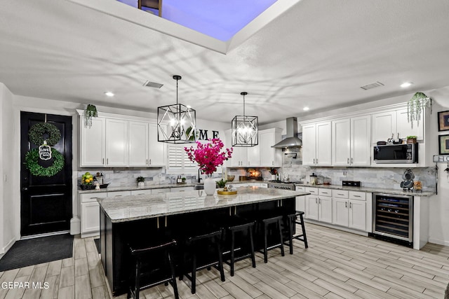 kitchen featuring a center island, white cabinetry, wine cooler, and wall chimney exhaust hood