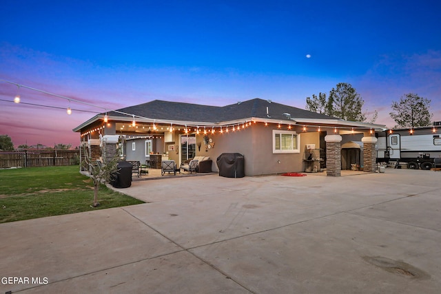 back house at dusk with a yard and a patio