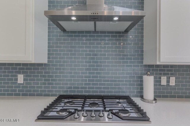 room details featuring stainless steel gas cooktop, white cabinetry, exhaust hood, and tasteful backsplash