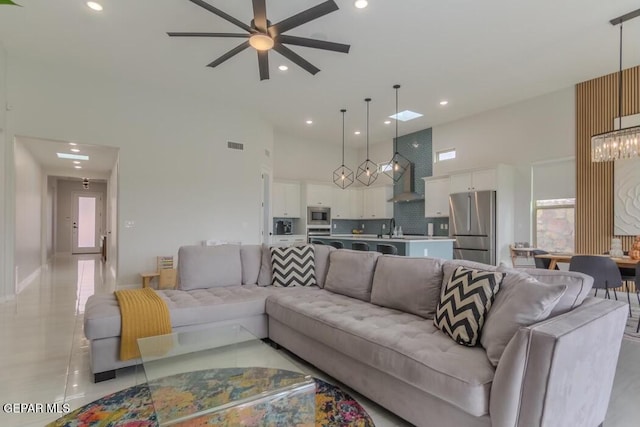 living room with ceiling fan, sink, a towering ceiling, and light tile patterned floors