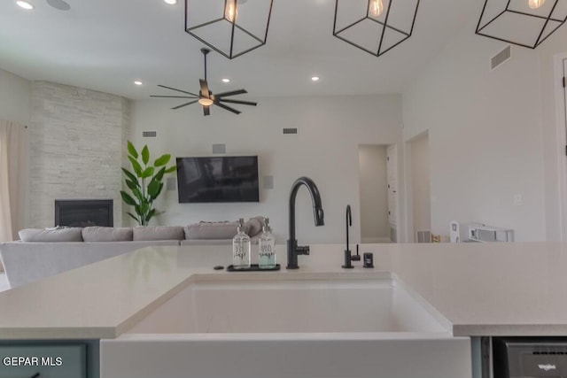 kitchen featuring ceiling fan, a large fireplace, dishwasher, and sink