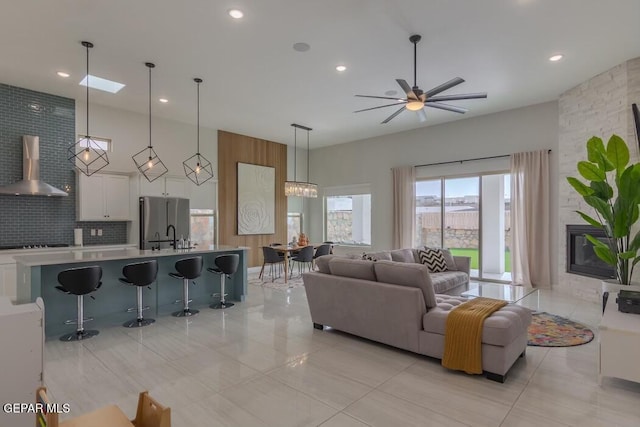 tiled living room with ceiling fan with notable chandelier, a large fireplace, and sink