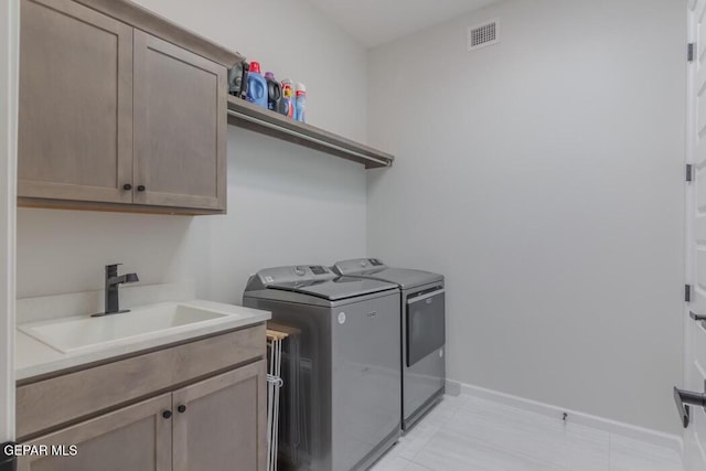 laundry area featuring washer and clothes dryer, cabinets, and sink