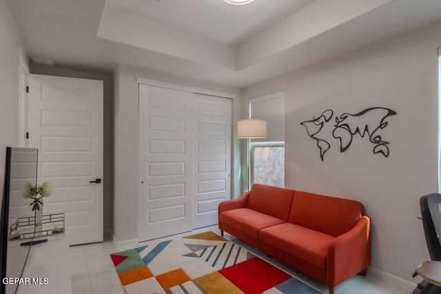 living room featuring a tray ceiling and light tile patterned flooring