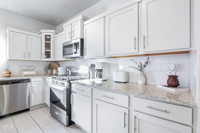 kitchen featuring light tile patterned flooring, decorative backsplash, white cabinets, and stainless steel appliances