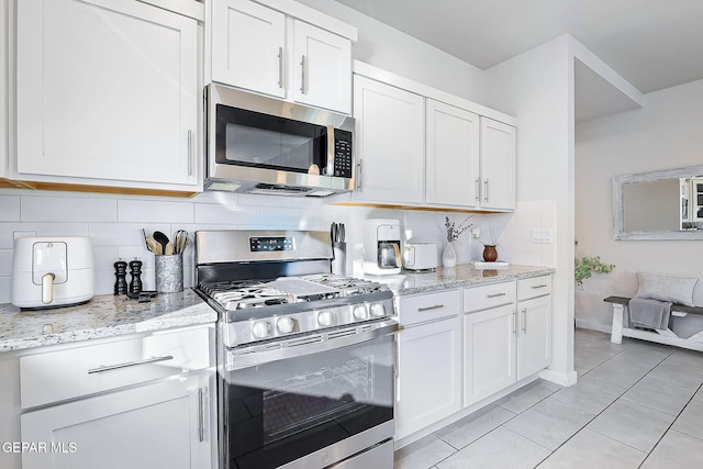 kitchen featuring light stone countertops, stainless steel appliances, white cabinetry, and tasteful backsplash