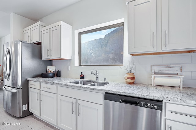 kitchen featuring light stone counters, stainless steel appliances, white cabinetry, and sink