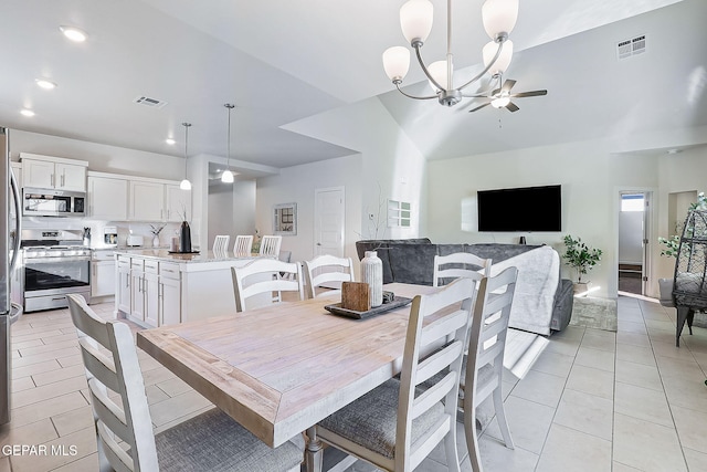 dining room with ceiling fan with notable chandelier, light tile patterned floors, and vaulted ceiling