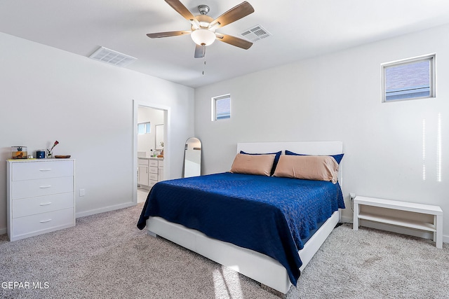 bedroom featuring light colored carpet, ensuite bath, and ceiling fan