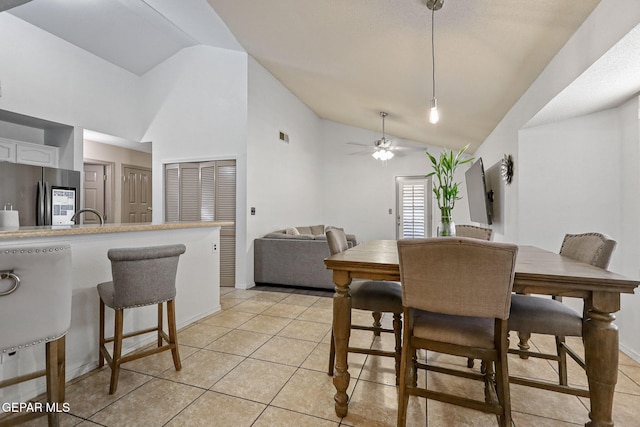 dining area with light tile patterned floors, high vaulted ceiling, and ceiling fan