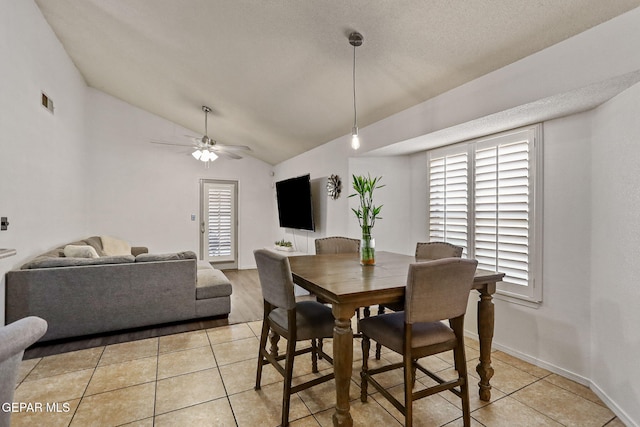 dining room with light tile patterned floors, a textured ceiling, ceiling fan, and lofted ceiling