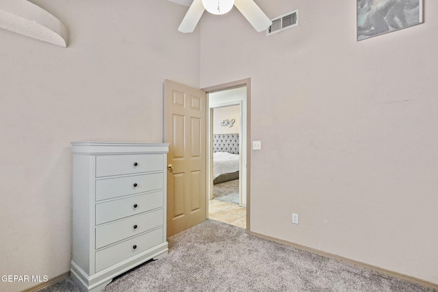 unfurnished bedroom with ceiling fan, light colored carpet, and a high ceiling