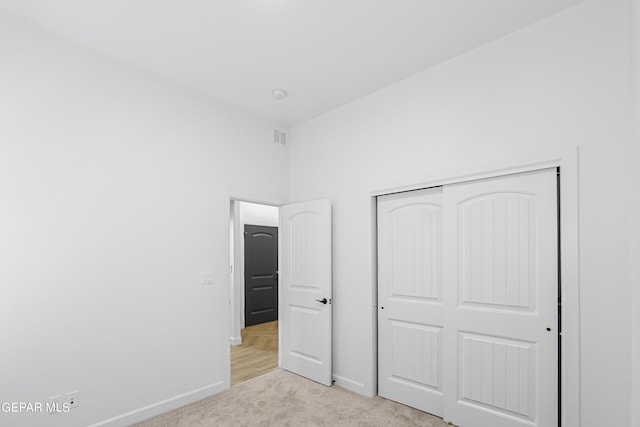 unfurnished bedroom featuring light carpet and a closet