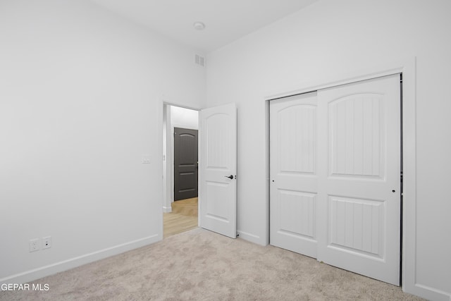 unfurnished bedroom featuring light carpet and a closet