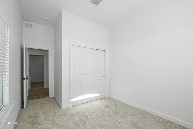 unfurnished bedroom featuring light colored carpet and a closet