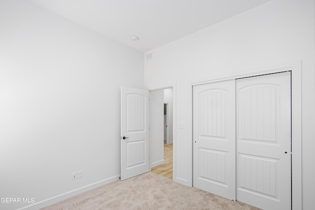 unfurnished bedroom with light carpet and a closet