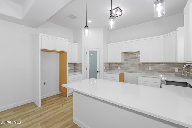 kitchen featuring decorative backsplash, pendant lighting, light hardwood / wood-style floors, and white cabinetry