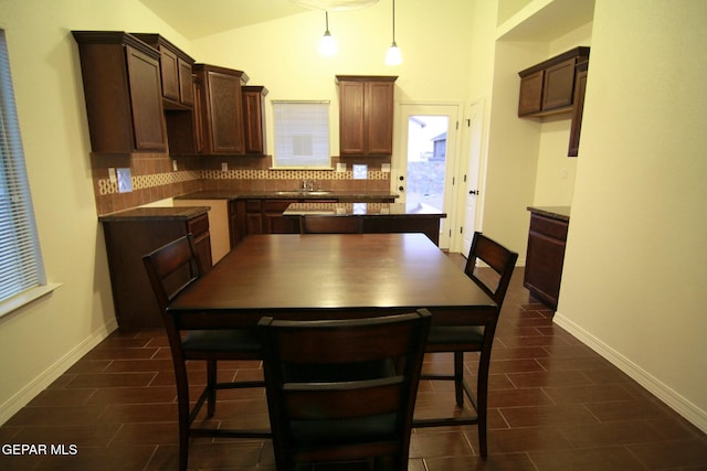 kitchen with decorative light fixtures, dark brown cabinets, lofted ceiling, and tasteful backsplash