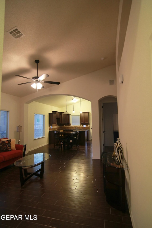 living room with ceiling fan, dark wood-type flooring, and vaulted ceiling