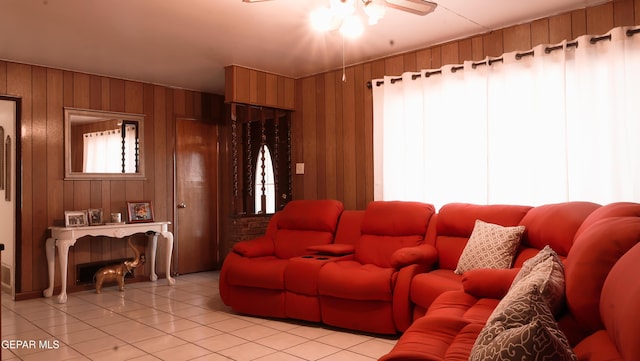 tiled living room featuring ceiling fan and wooden walls