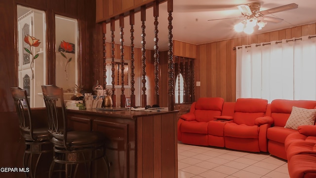 interior space with ceiling fan, bar area, and wood walls