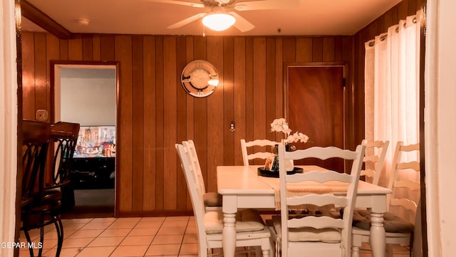 tiled dining area featuring wooden walls and ceiling fan