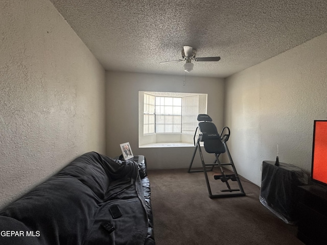 workout room with ceiling fan, dark carpet, and a textured ceiling