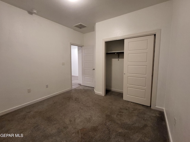 unfurnished bedroom featuring a closet and dark carpet