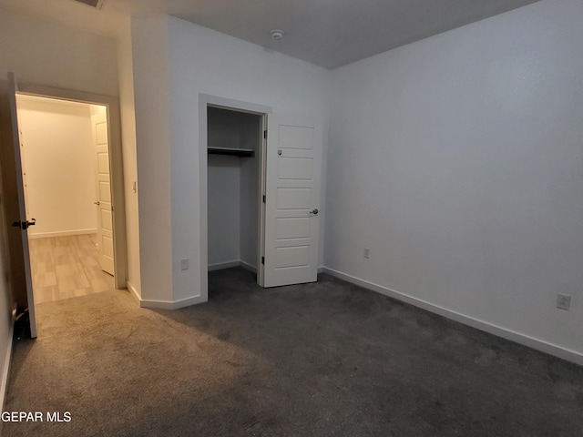 unfurnished bedroom with dark carpet and a closet