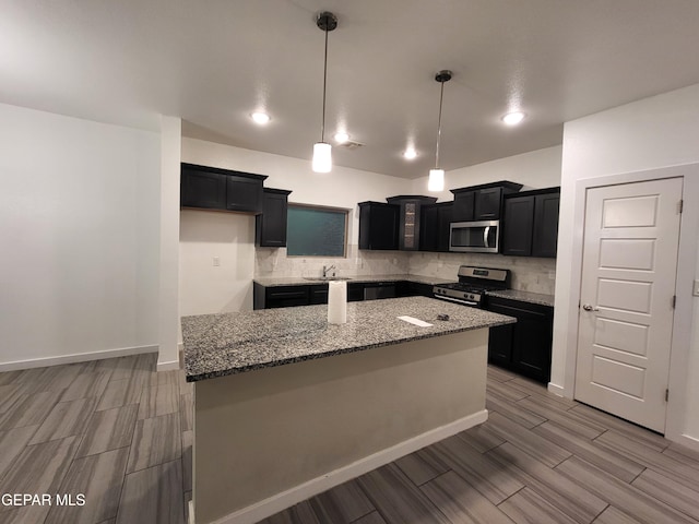 kitchen with pendant lighting, light hardwood / wood-style flooring, stone countertops, a kitchen island, and stainless steel appliances