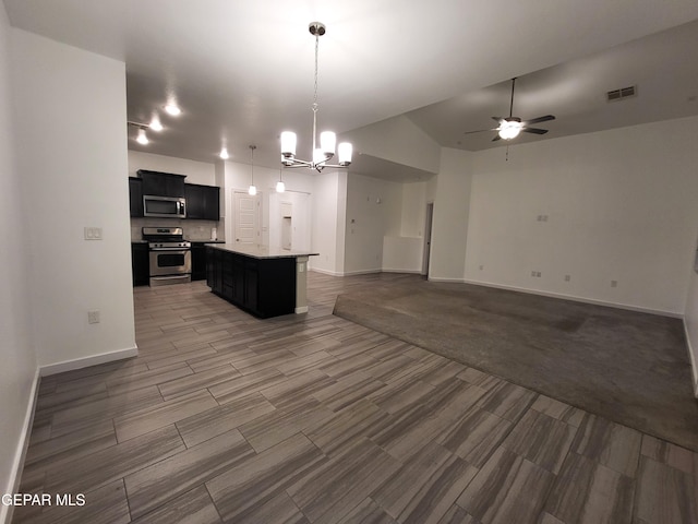 kitchen featuring pendant lighting, a center island, ceiling fan with notable chandelier, hardwood / wood-style flooring, and appliances with stainless steel finishes