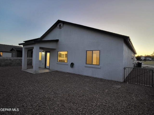 back house at dusk with central air condition unit and a patio