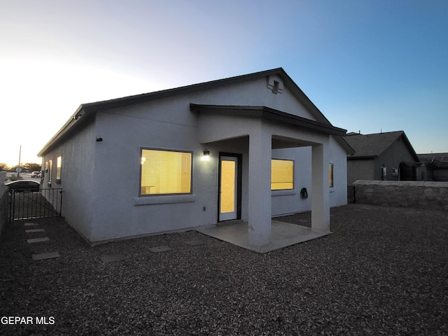 back house at dusk featuring a patio