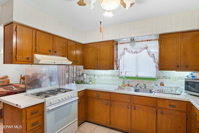 kitchen with tasteful backsplash, white gas range, sink, and light tile patterned flooring