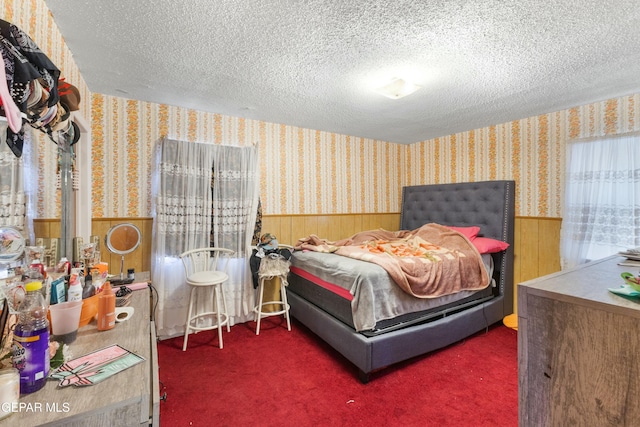 bedroom featuring wooden walls, a textured ceiling, and dark colored carpet