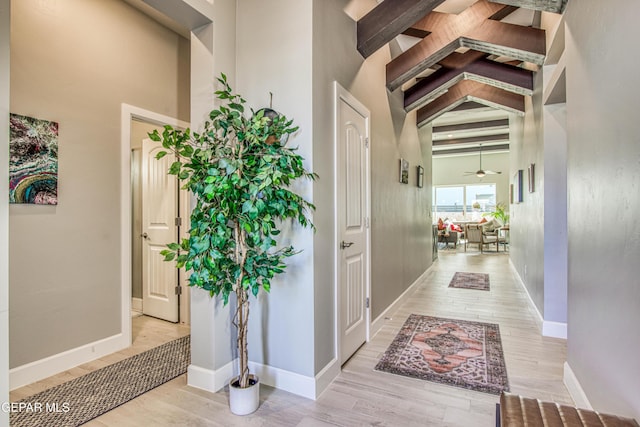 interior space featuring beamed ceiling, a towering ceiling, light wood-type flooring, and ceiling fan