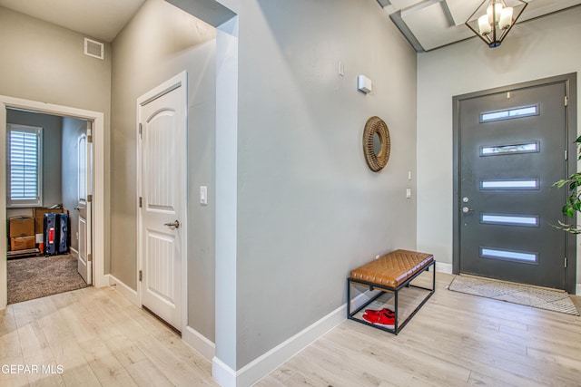 foyer entrance with an inviting chandelier and light hardwood / wood-style flooring