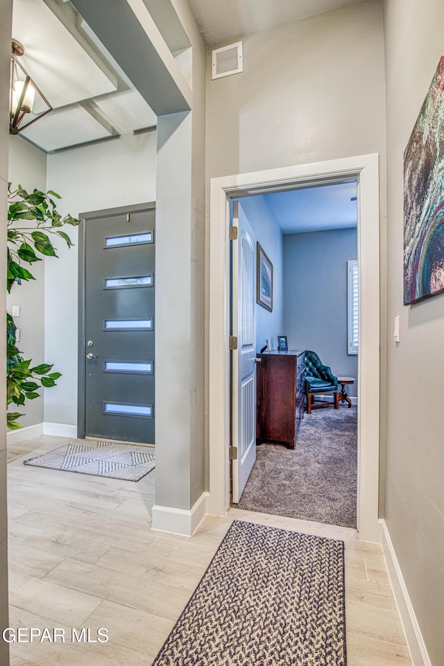 foyer entrance with light wood-type flooring and a chandelier