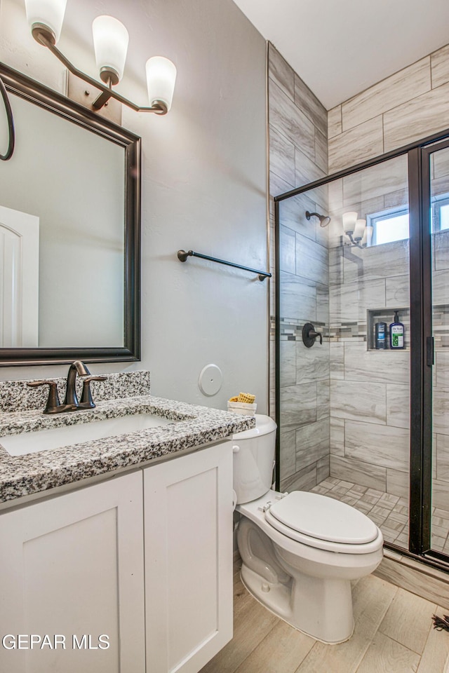 bathroom featuring wood-type flooring, vanity, toilet, and an enclosed shower