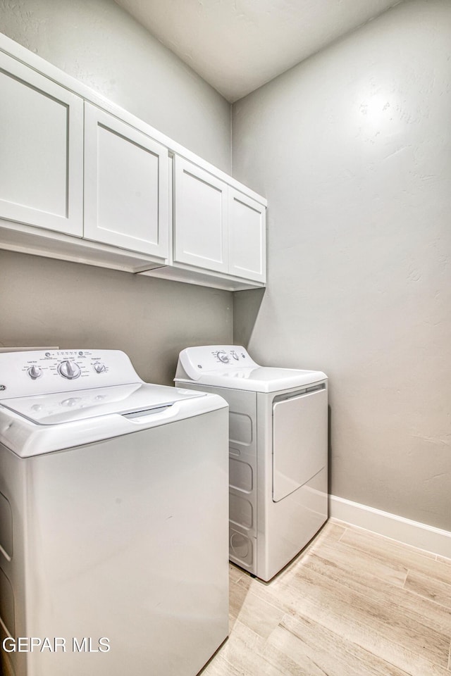 laundry area with cabinets, light hardwood / wood-style flooring, and washing machine and clothes dryer