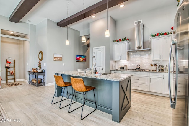 kitchen featuring white cabinets, wall chimney exhaust hood, pendant lighting, and stainless steel appliances