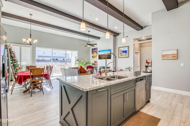 kitchen featuring sink, light stone counters, light wood-type flooring, and a kitchen island with sink