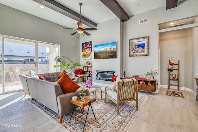 living room featuring beam ceiling, a towering ceiling, light hardwood / wood-style floors, and ceiling fan