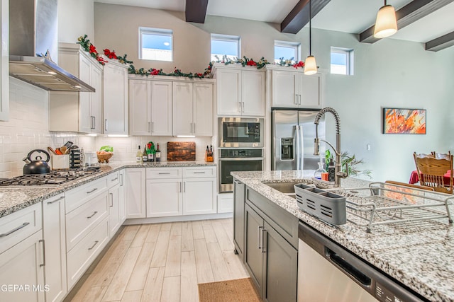 kitchen featuring light stone countertops, appliances with stainless steel finishes, wall chimney exhaust hood, beamed ceiling, and white cabinets