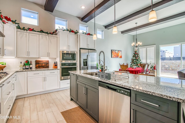 kitchen with a wealth of natural light, white cabinetry, pendant lighting, and stainless steel appliances